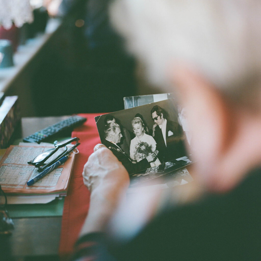 An elderly person looking at old photographs, a moment of reflection on memories and family.