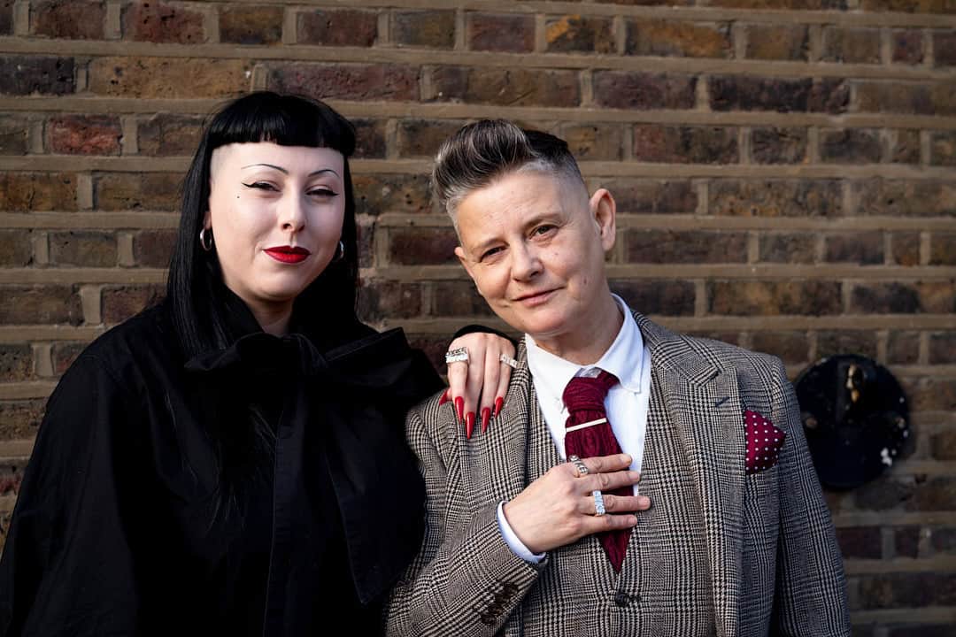 Couple posing in stylish outfits wearing Amy Spalding’s jewelry, honoring sapphic legacy and LGBTQ+ pride.