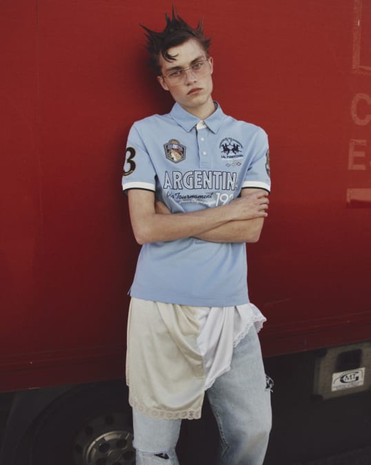 A young man standing in front of a red truck