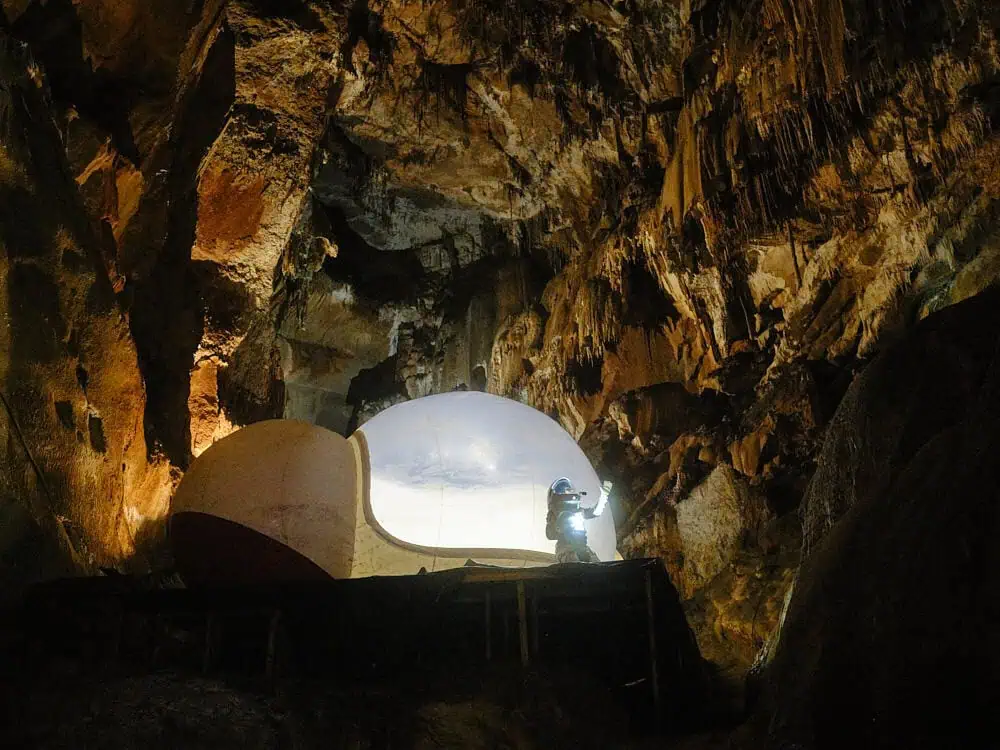 Space capsule installation inside a cave with Nelly Ben Hayoun-Stépanian exploring with flashlight