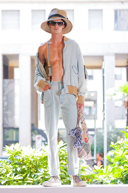 Model in light denim bomber jacket, straw hat, and cuffed jeans from Vivienne Westwood Men’s Spring/Summer collection at Milan Fashion Week.