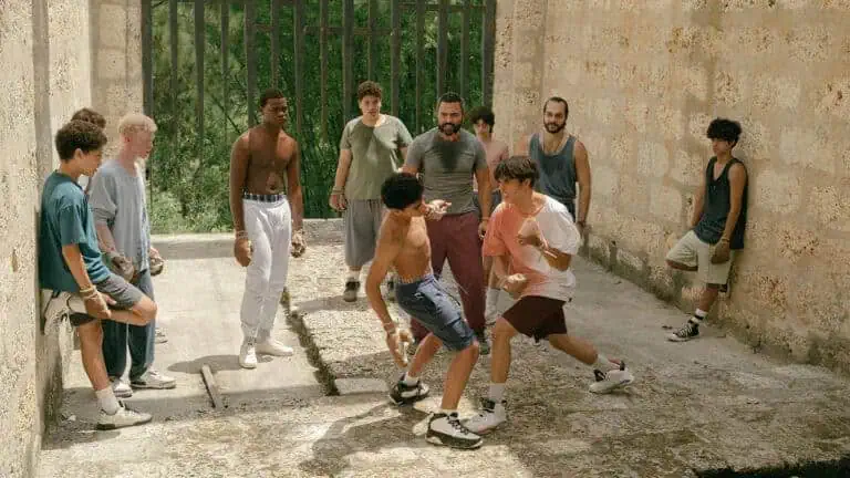 Teen boys boxing in stone courtyard under adult supervision, tigueraje training in Tiguere