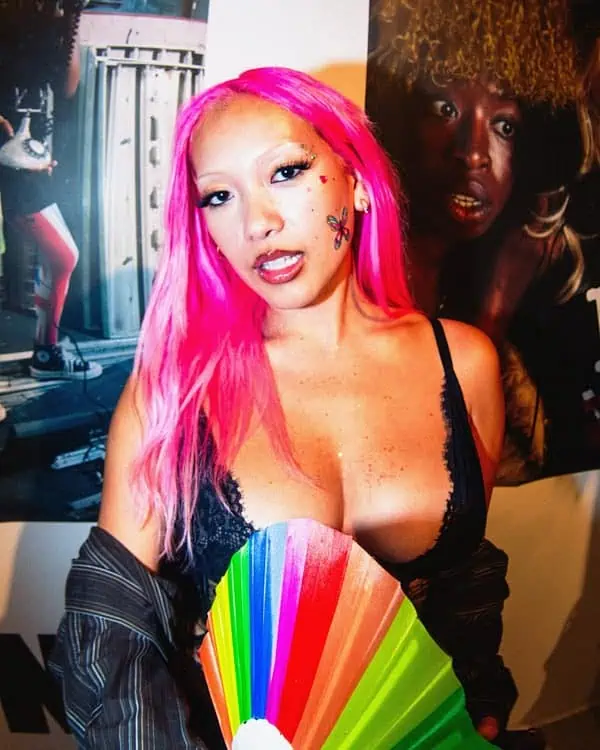 Portrait of a pink-haired artist holding a rainbow fan at the A Voice Amplified event in London.