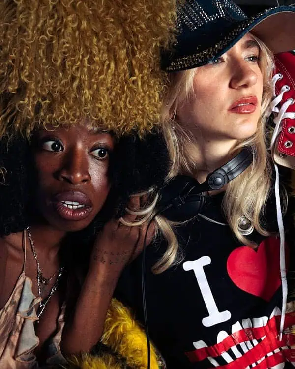 Close-up of two artists in bold headwear and layered fashion at A Voice Amplified, celebrating European creative expression