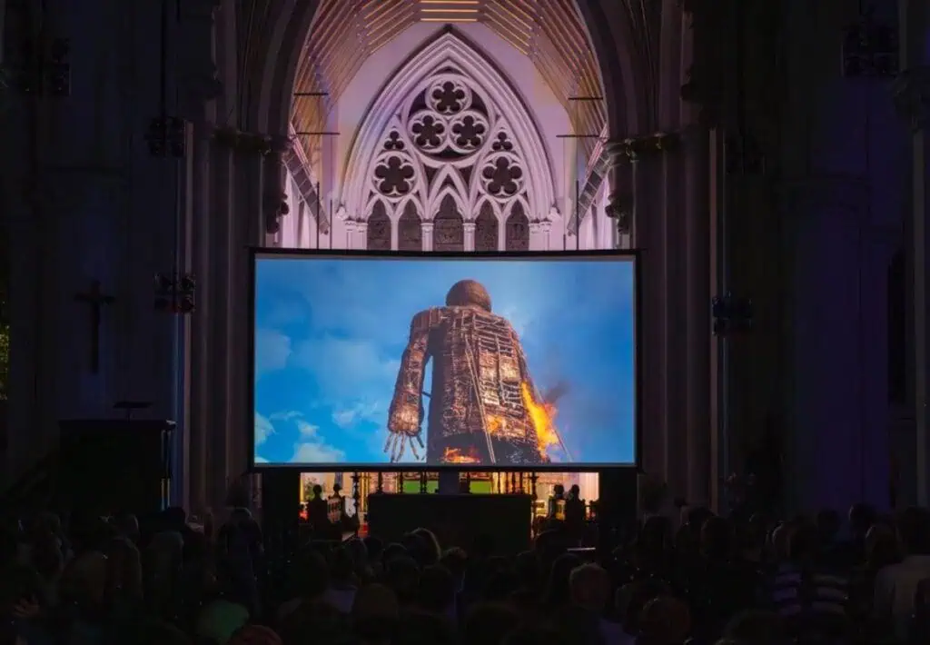 Screening of the film 'The Wicker Man' inside a Gothic church, with an audience seated in front of the large screen.
