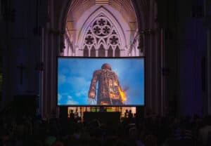 Screening of the film 'The Wicker Man' inside a Gothic church, with an audience seated in front of the large screen.