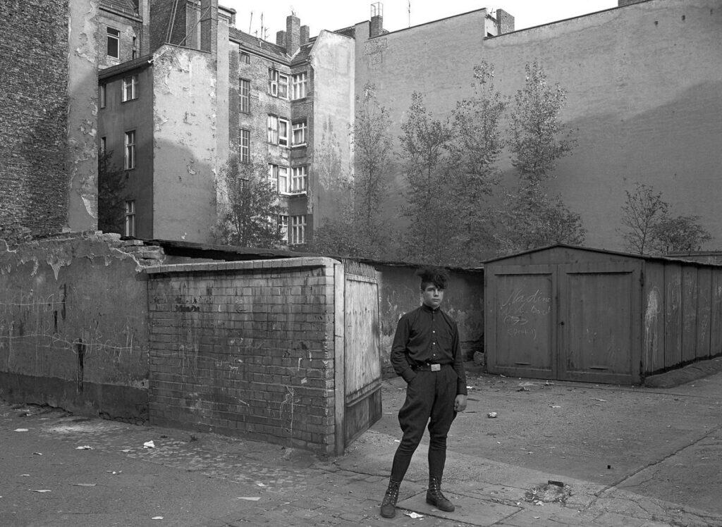 Black and white photograph of a young man standing in a decayed East Berlin courtyard, 1981, by photographer Harf Zimmermann.
