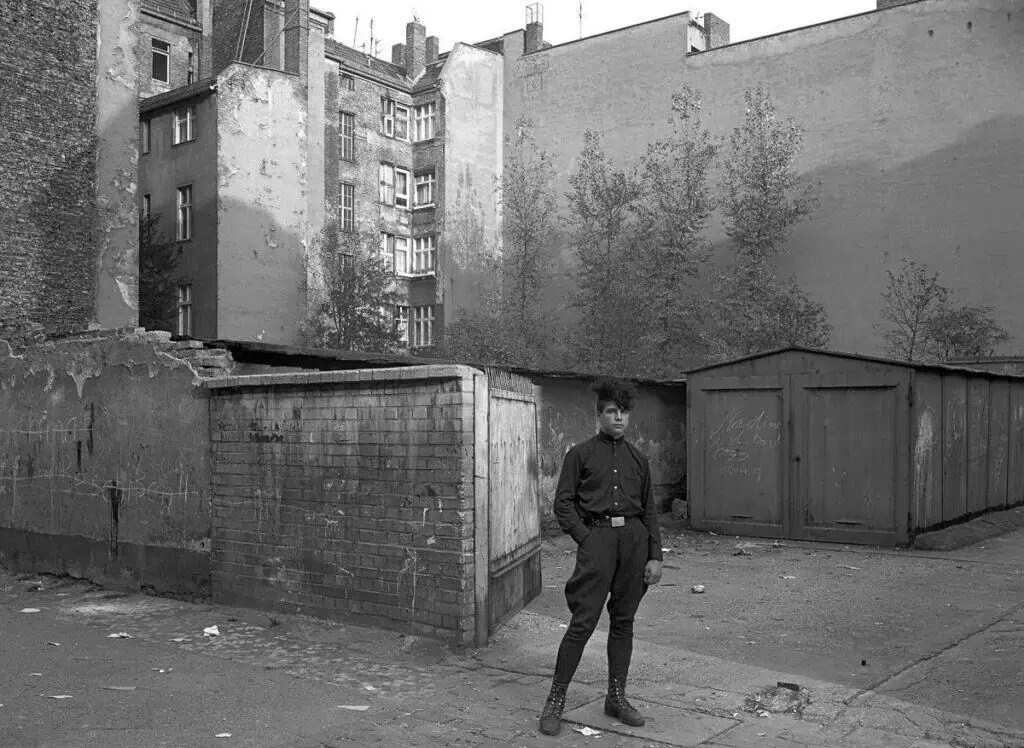 Black and white photograph of a young man standing in a decayed East Berlin courtyard, 1981, by photographer Harf Zimmermann.