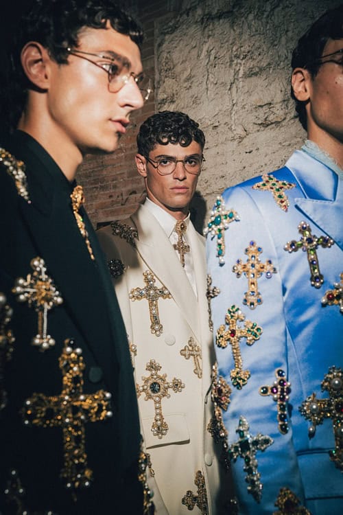 Close-up of three models in suits adorned with jeweled crosses, showcasing luxury tailoring – Dolce & Gabbana Alta Sartoria 2025.