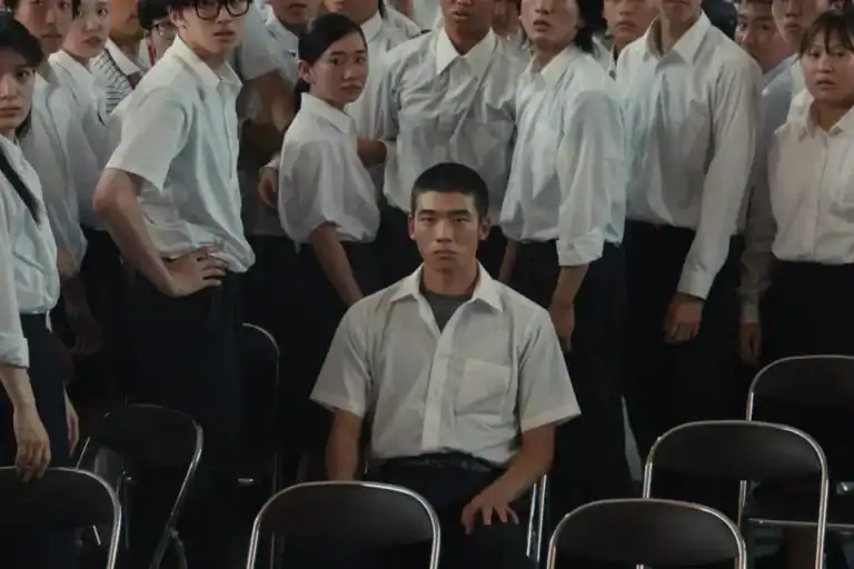 Kou sits isolated among classmates during a tense school assembly in Happyend.