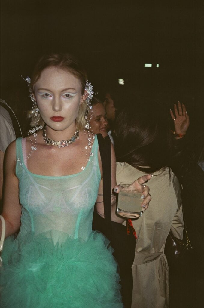 Guest wearing sheer green tulle dress at H&M London Fashion Week party.