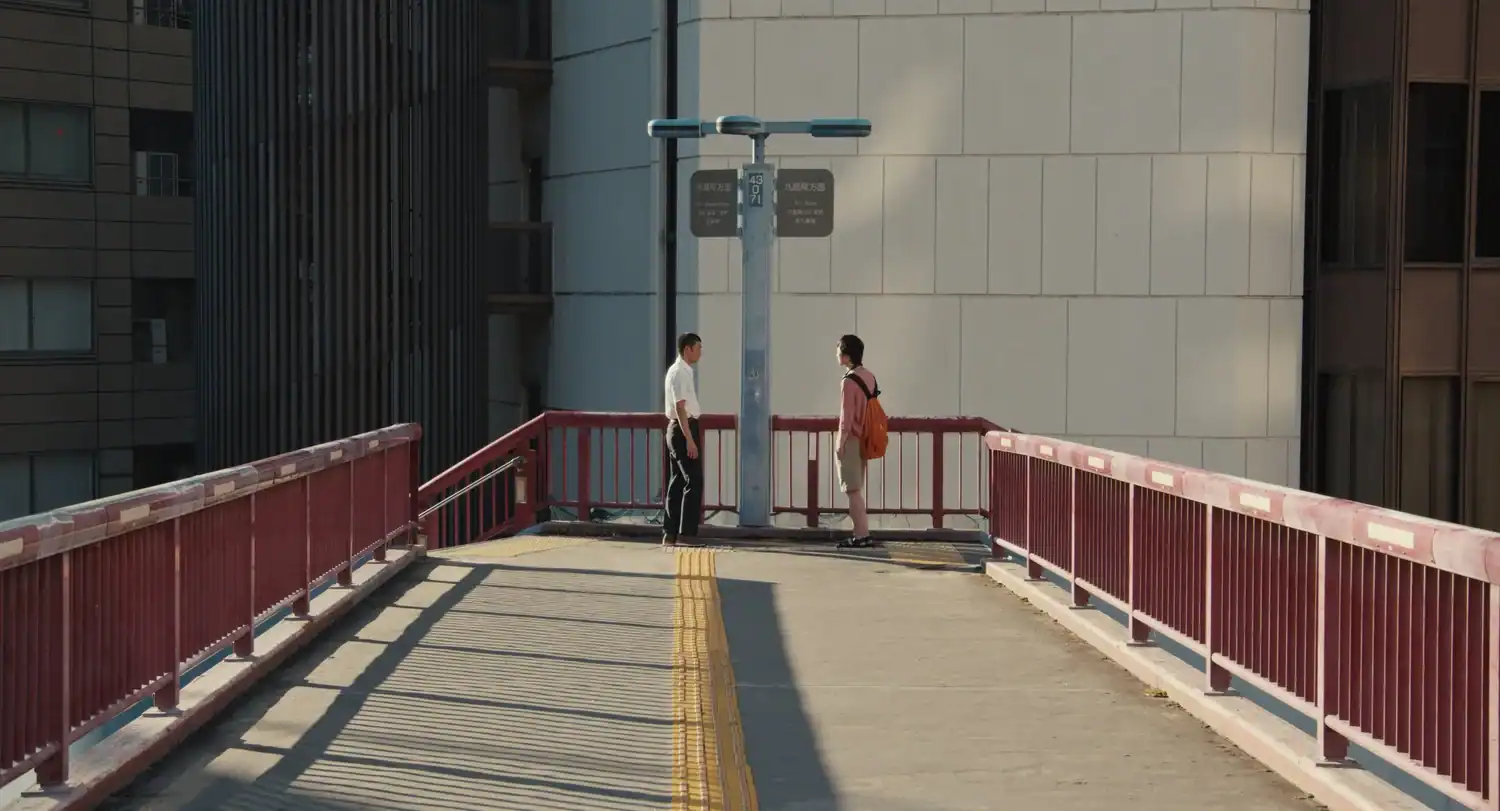 Kou and Yuta stand on an empty pedestrian bridge in Tokyo in a still from Happyend.