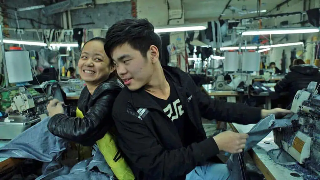 Young garment workers smiling in Zhili textile factory, Wang Bing’s Youth (Spring).