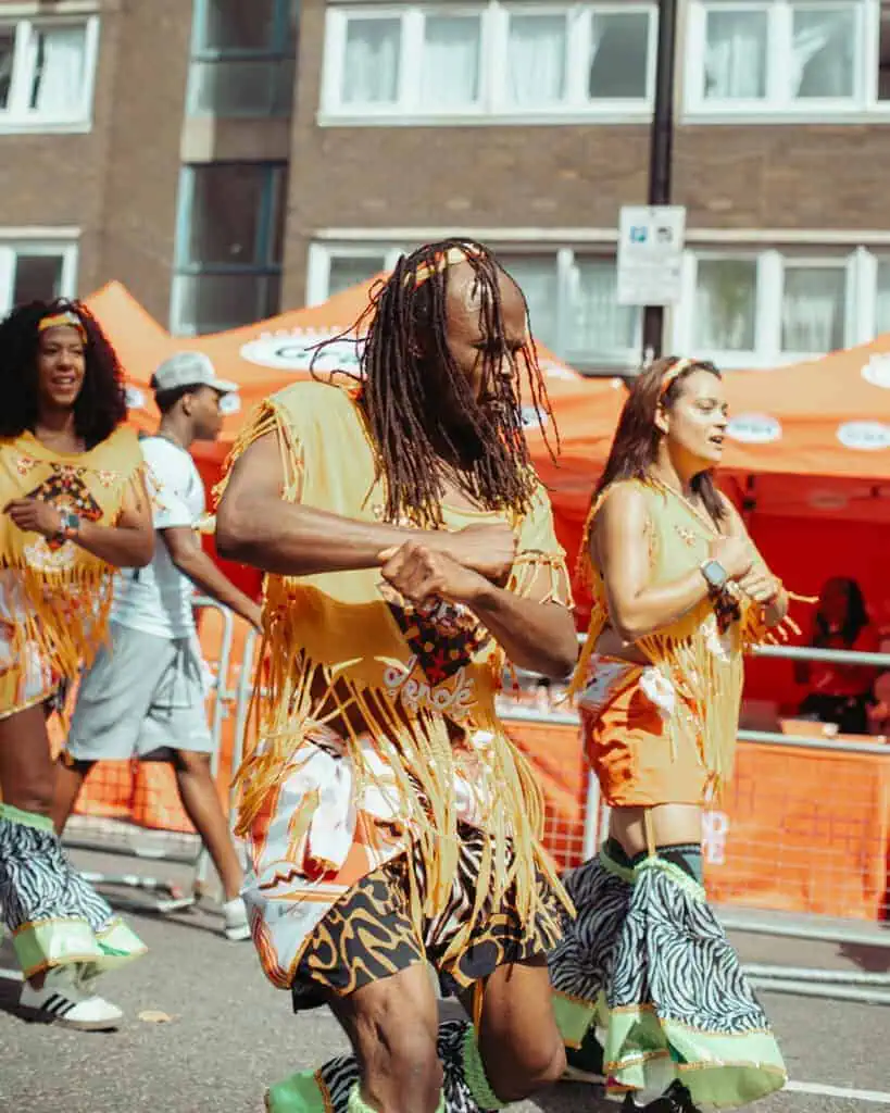Dancers in yellow fringe costumes performing at Notting Hill Carnival.