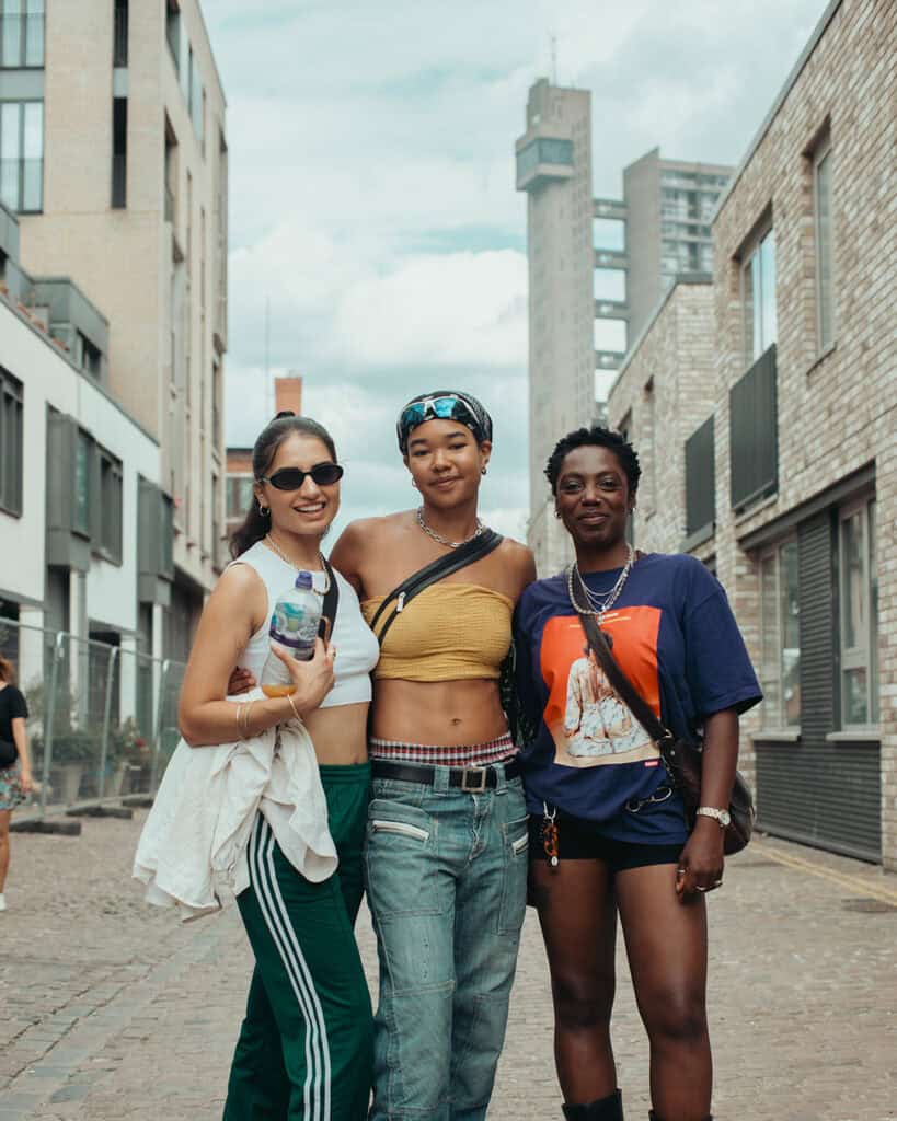 hree friends posing together in the streets during Notting Hill Carnival.