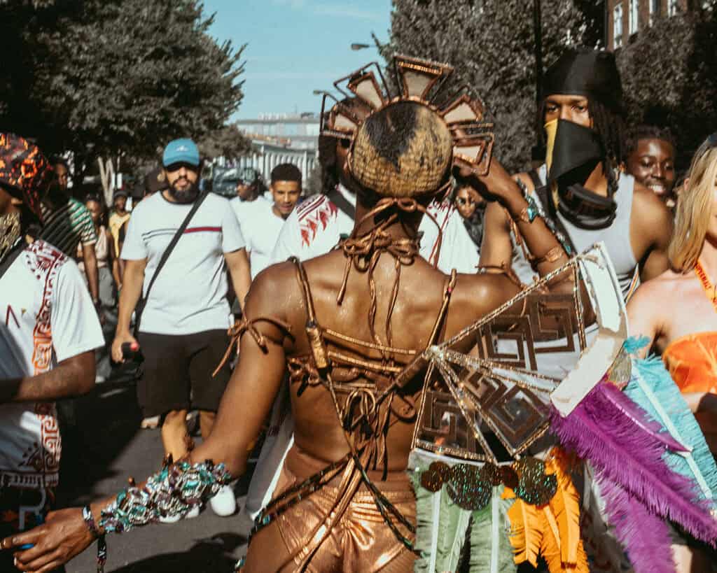 Mas dancer in bronze costume leading the crowd at Notting Hill Carnival.