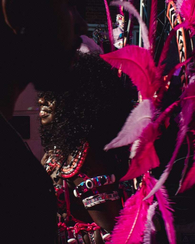 Carnival performer wearing pink feathers and beads at Notting Hill Carnival.