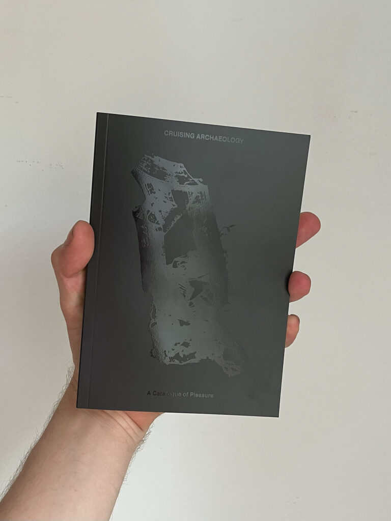 Hand holding a copy of the “Cruising Archaeology” art book by SMUT PRESS, photographed for Cold Magazine interview with founder Jack Scollard.