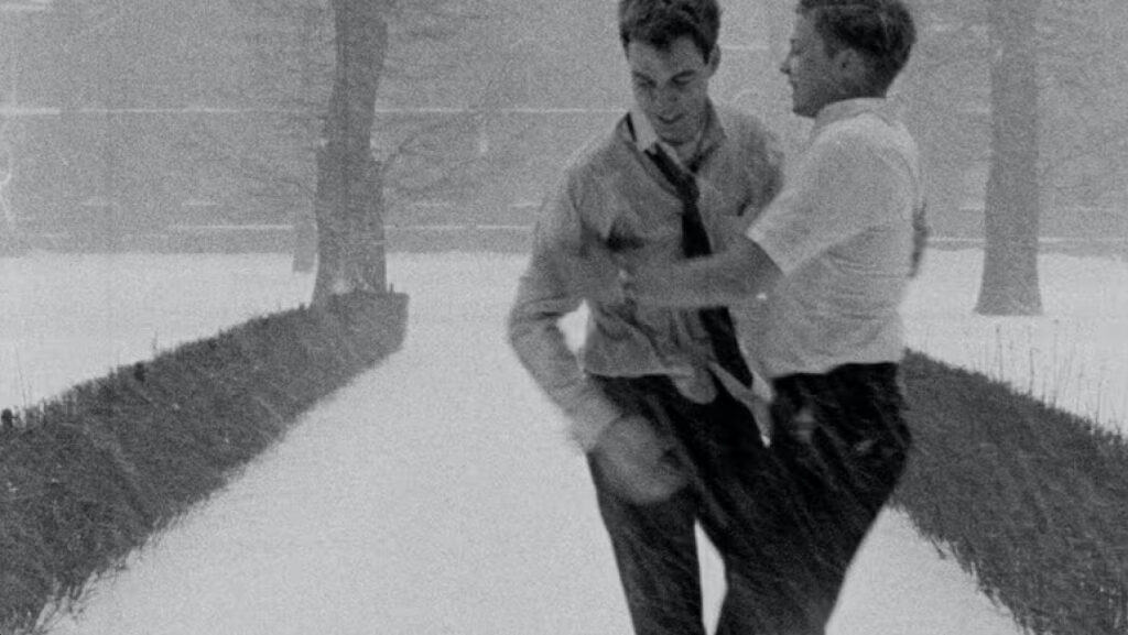 Scene from Winter Kept Us Warm (1965) showing two men joyfully playing in the snow, symbolizing intimacy and emotional connection.