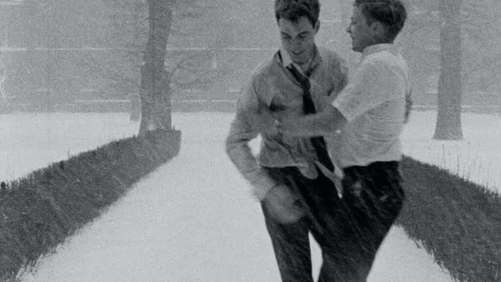 Scene from Winter Kept Us Warm (1965) showing two men joyfully playing in the snow, symbolizing intimacy and emotional connection.