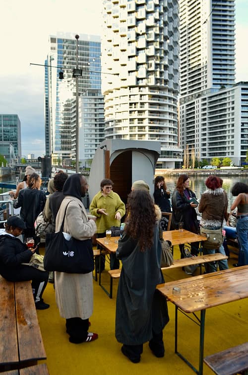 Guests gathering on a boat terrace at Canary Wharf during a Sapphic Cinema queer film event.