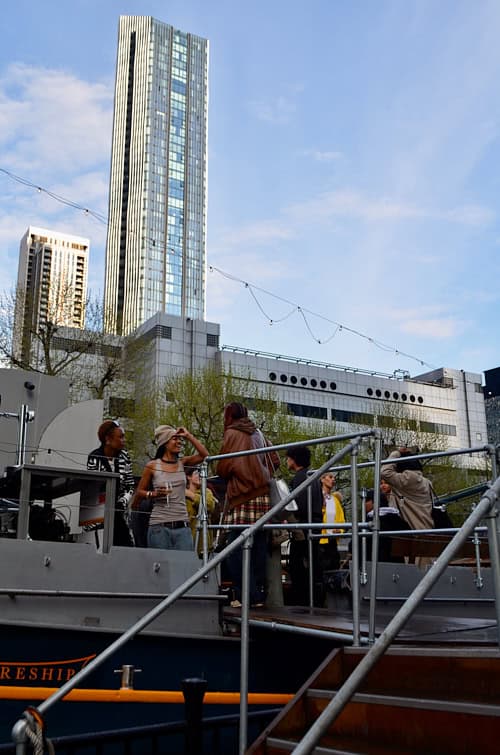 Crowd mingling on the upper deck of the moored boat hosting the Sapphic Cinema event.