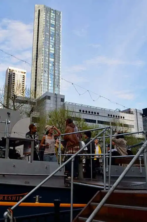 Crowd mingling on the upper deck of the moored boat hosting the Sapphic Cinema event.