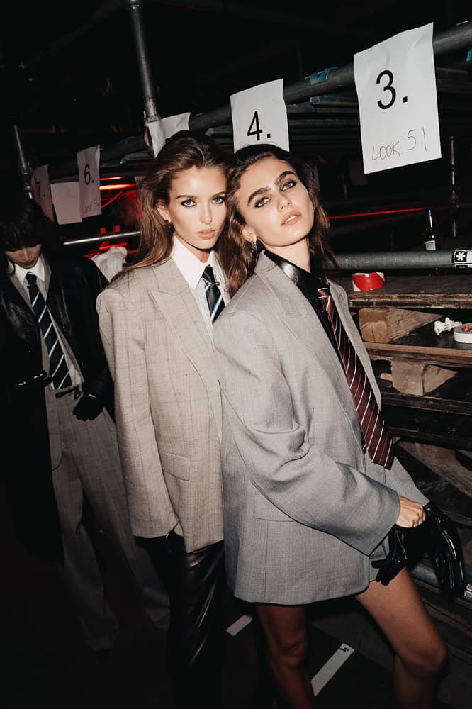 Models in oversized blazers and ties backstage at H&M London Fashion Week show.