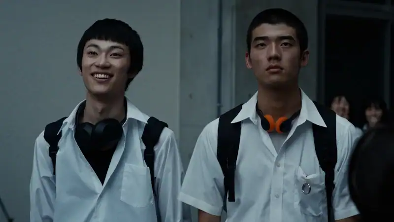 Kou and Yuta walk to school in uniform with headphones in a scene from Happyend.