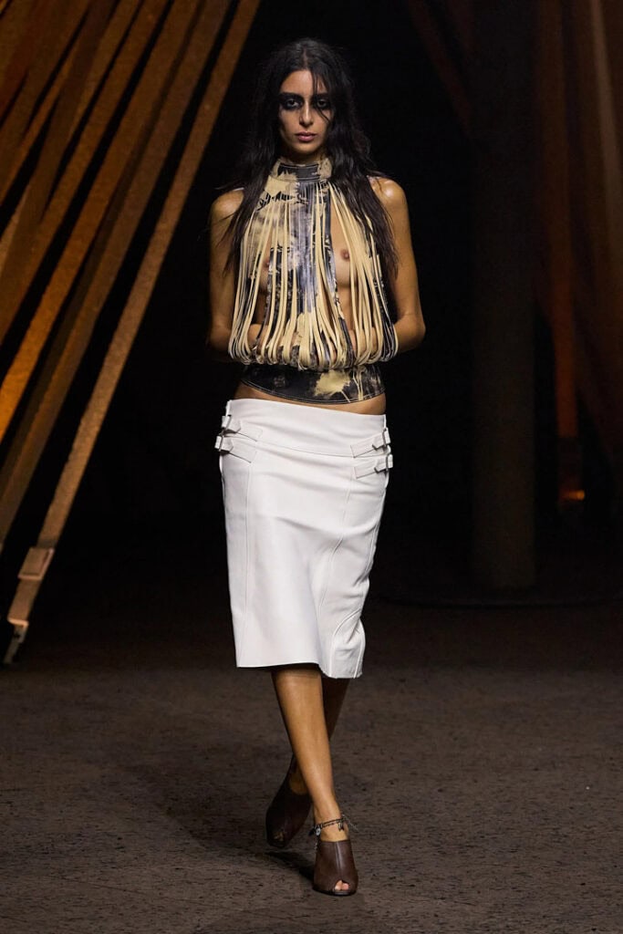 Alexander McQueen SS26 fringed halter top in metallic tones paired with a structured white skirt.