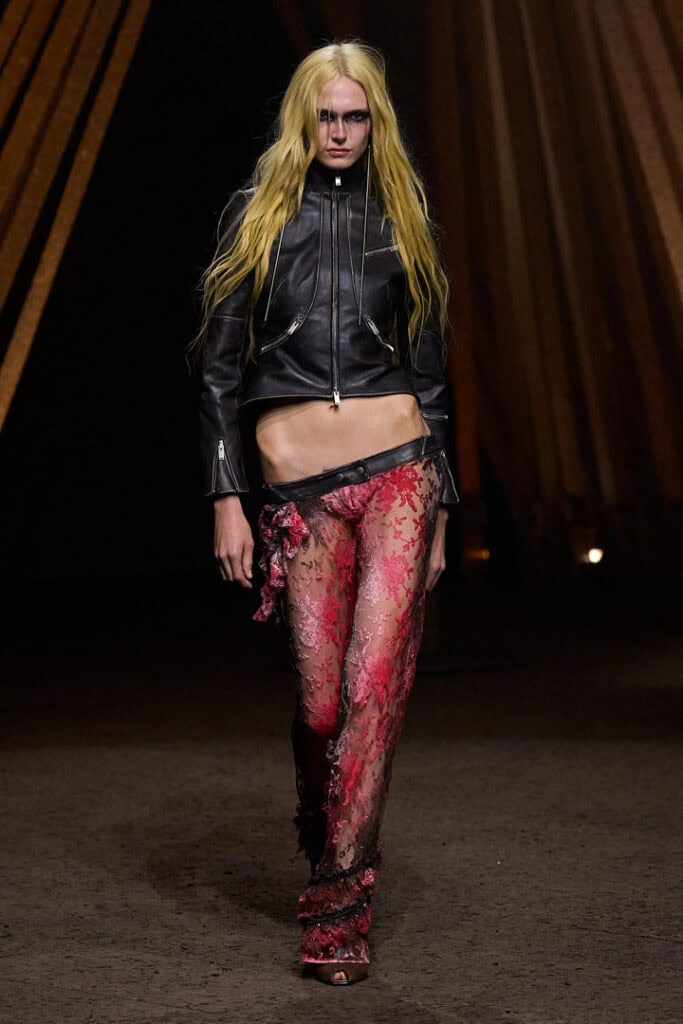 Alexander McQueen SS26 black leather jacket styled with sheer red textured trousers.