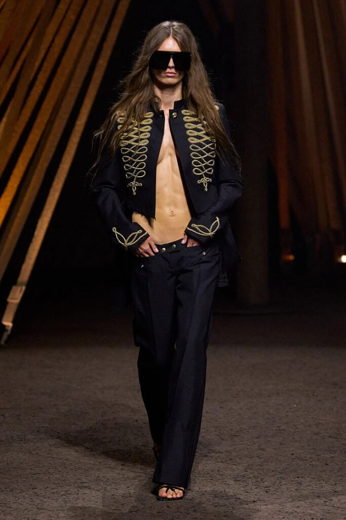 Alexander McQueen SS26 black tailored jacket with gold military embroidery and wide-leg trousers on the runway.
