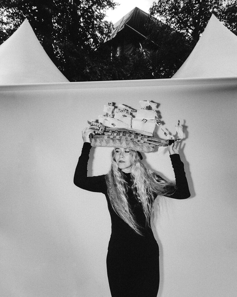 Anna von Hausswolff with long blonde hair wearing a colorful ship-shaped headpiece, color photograph by Fredrik Bengtsson for Cold Magazine promoting her album “ICONOCLASTS”.
