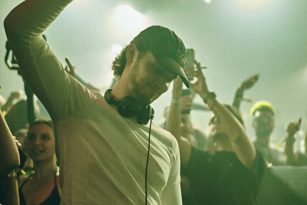 Intimate portrait of Mau P wearing headphones while DJing, green lighting and smoky atmosphere, promotional image for Cold Magazine interview on his new single “Tesla”.