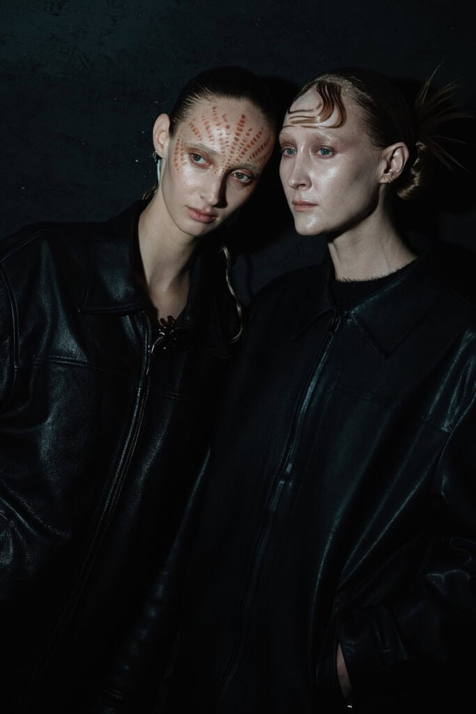 Models wearing dark sculptural garments from the Hengdi Wang x STIM Precious Metals collection, photographed in moody atmospheric lighting.