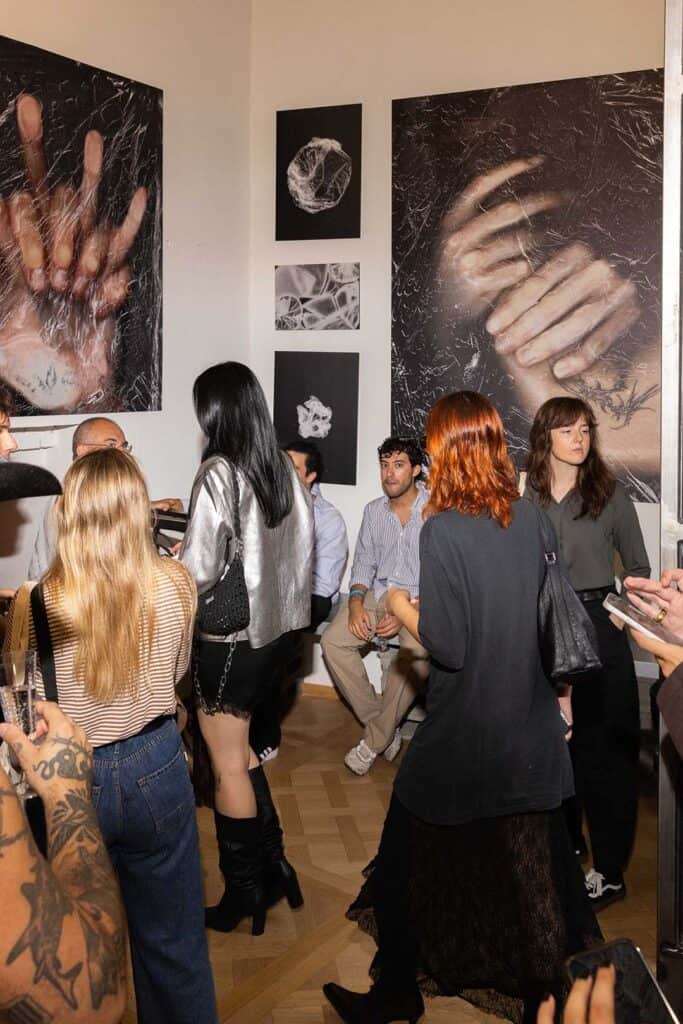 Gallery attendees viewing large photographs of distorted hands and bodies at Cate Colapietro’s “Breath Not Found” opening in Milan.