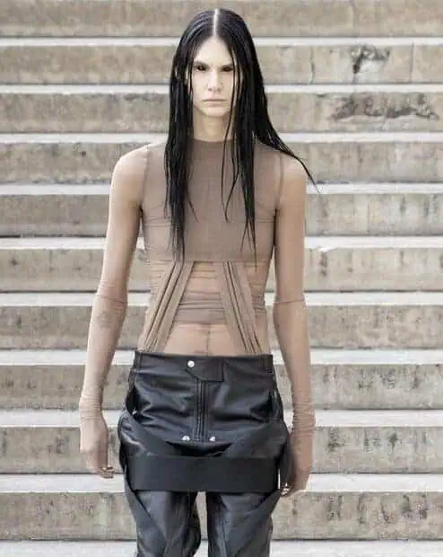 Rick Owens SS26 nude mesh top with exposed corset seams paired with black vinyl skirt.