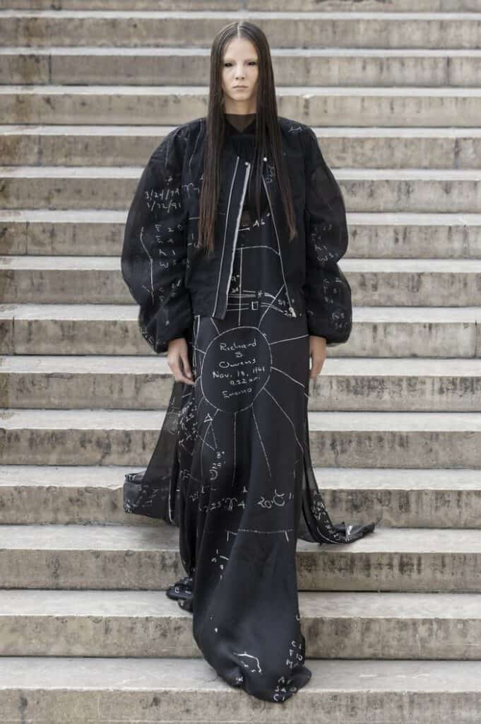 Rick Owens SS26 long black coat with chalk-like diagram print and oversized silhouette.