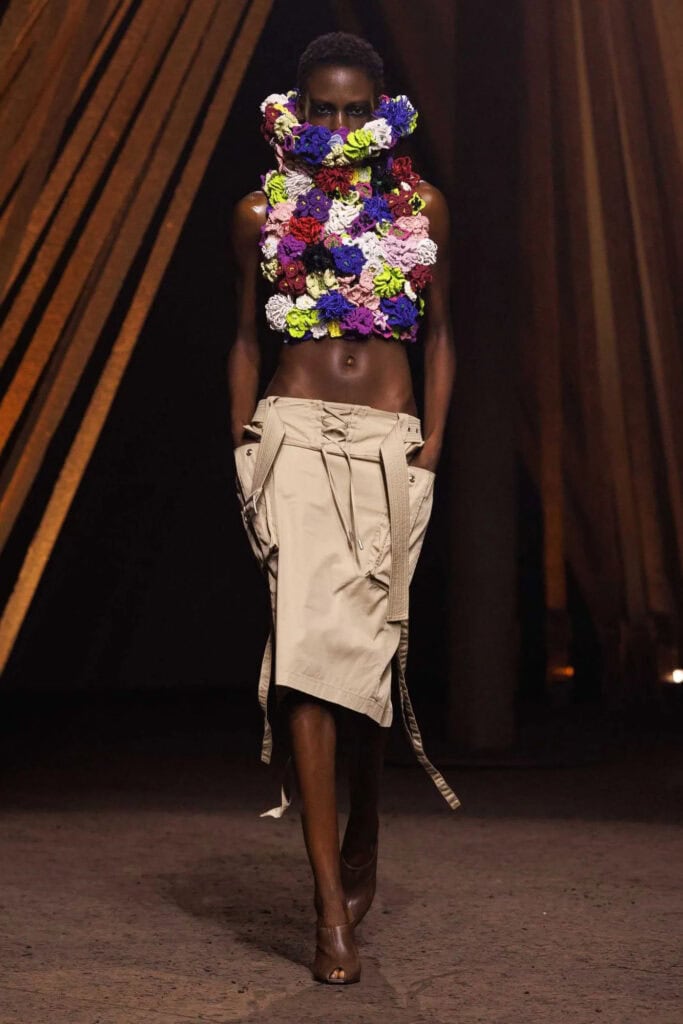 Alexander McQueen SS26 sculptural floral appliqué top paired with beige deconstructed cargo skirt on the runway.