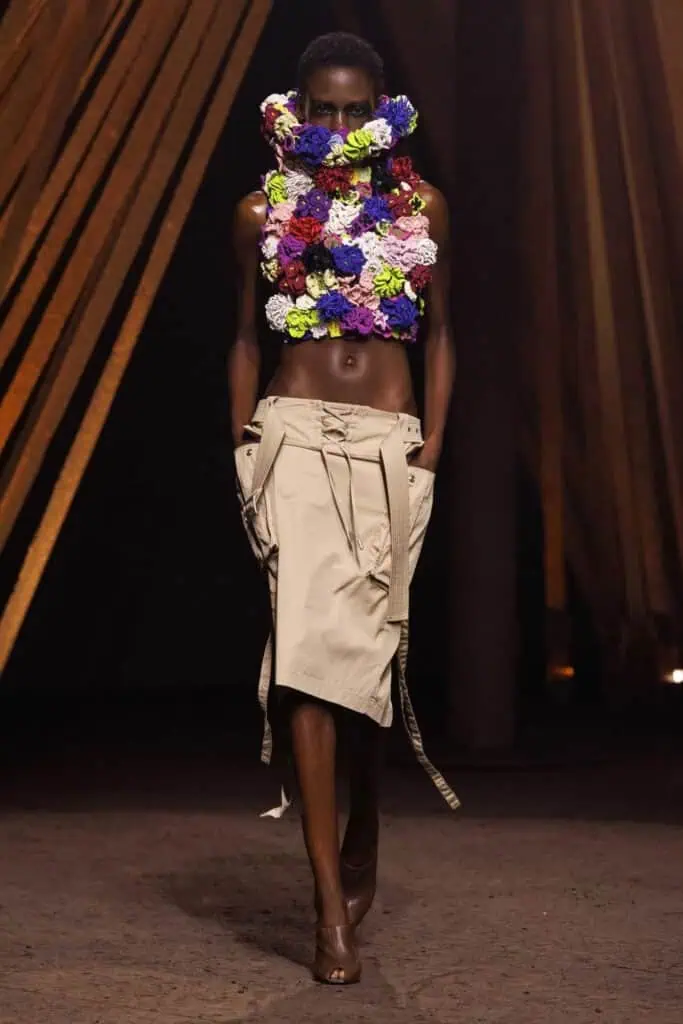 Alexander McQueen SS26 sculptural floral appliqué top paired with beige deconstructed cargo skirt on the runway.
