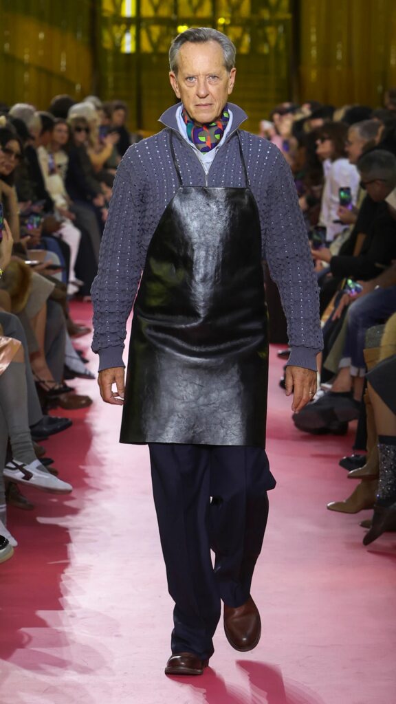 Miu Miu SS26 navy knit layered under black leather apron on the runway.