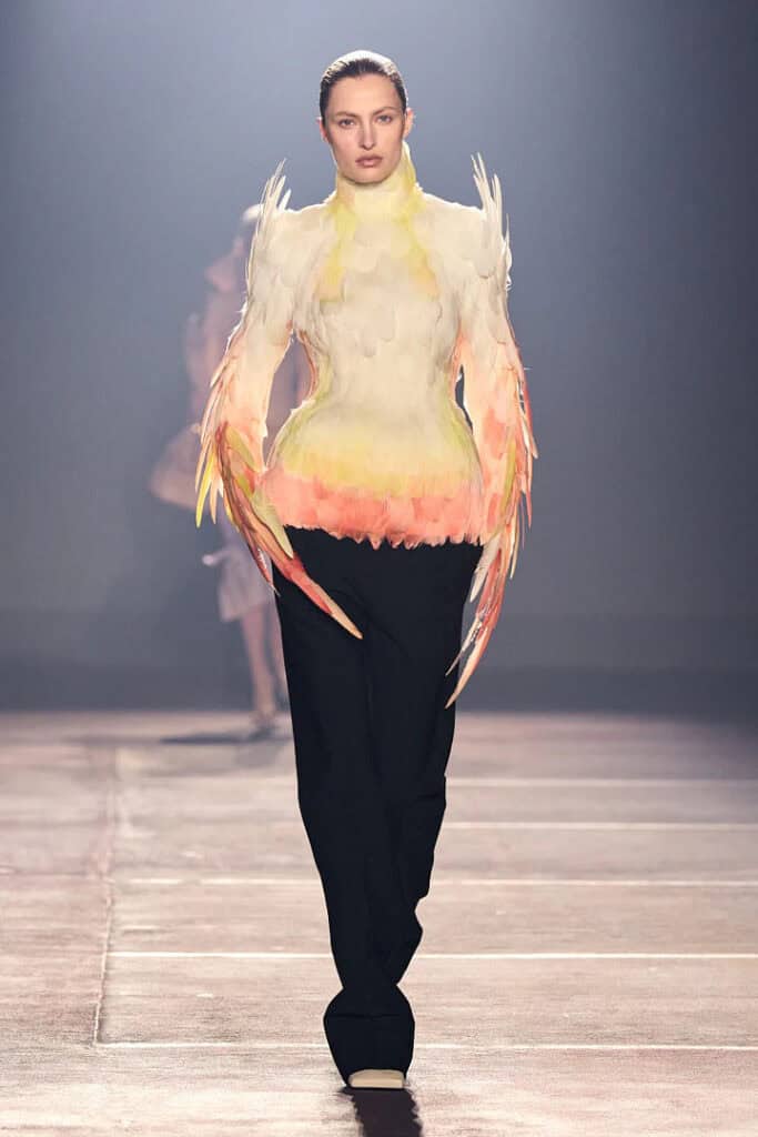 Mugler SS26 gradient feather-textured top in yellow and pink paired with black tailored trousers.
