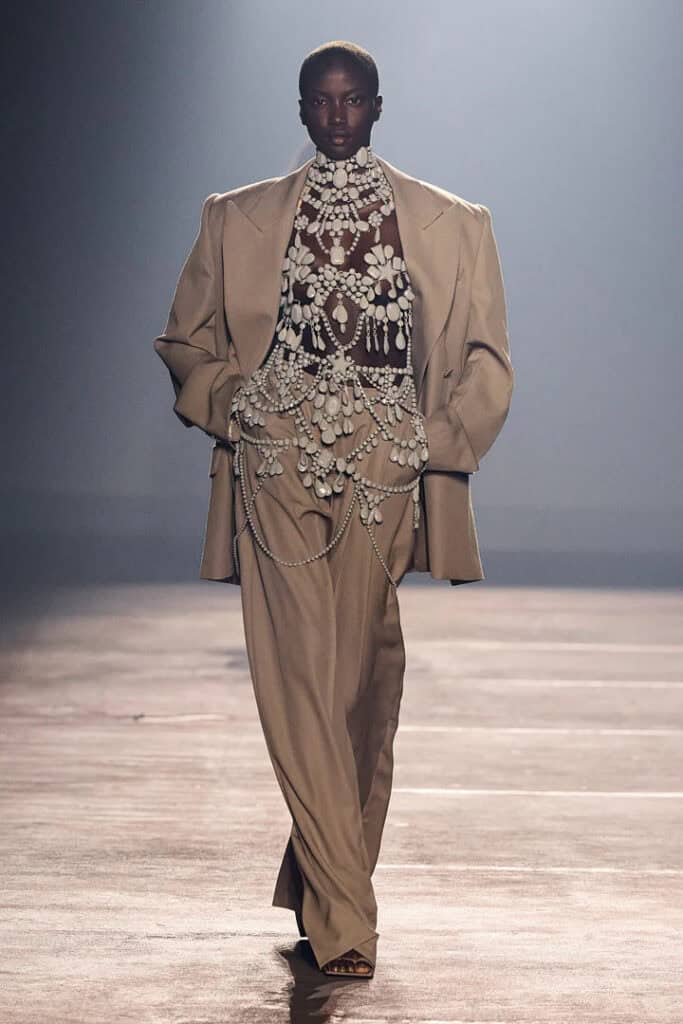 Mugler SS26 oversized camel blazer layered over embellished sculptural bodysuit with jeweled detailing.