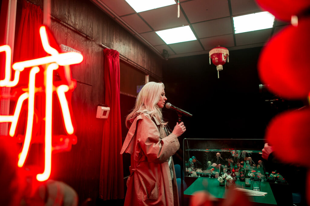Actor performing under red neon lights inside a Chinese restaurant set from “ROHTKO”, photographed by Artūrs Pavlovs for Cold Magazine article on Łukasz Twarkowski’s play at the Barbican Theatre.