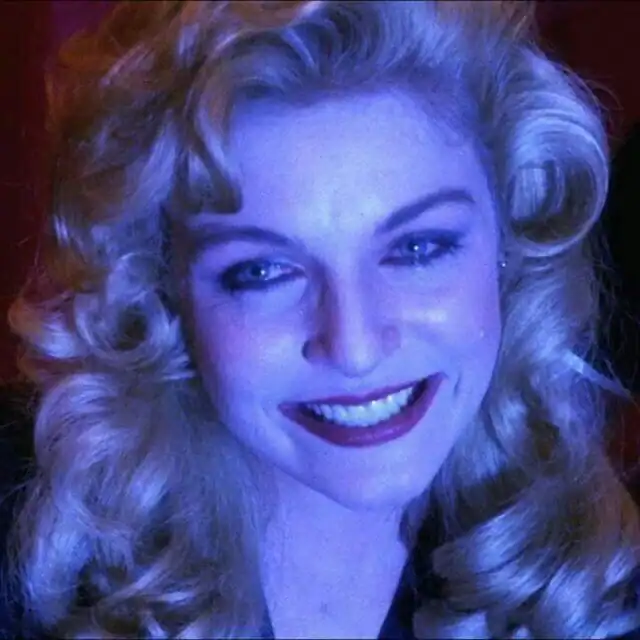 Close-up of a smiling woman bathed in cool blue lighting, reminiscent of dreamlike imagery in Twin Peaks.
