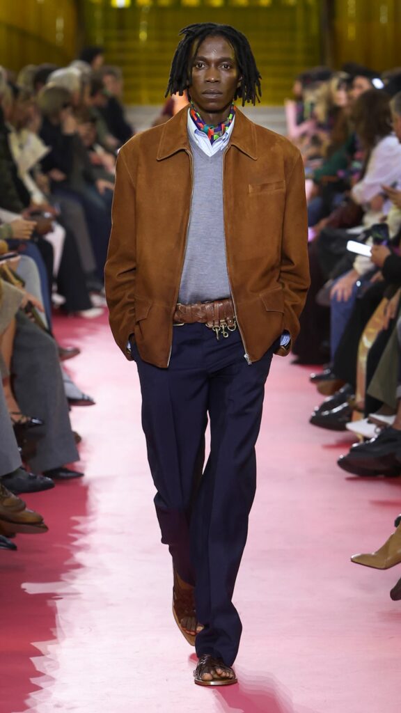 Miu Miu SS26 tan jacket over grey knit styled with navy trousers.