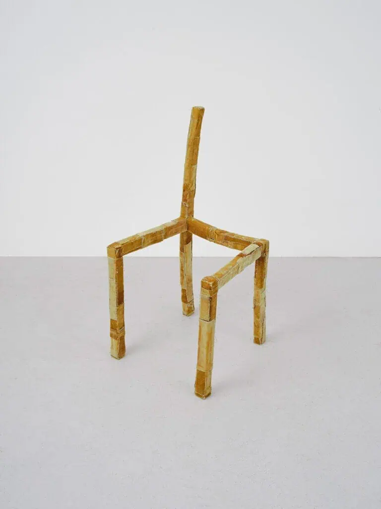 Alice Sheppard Fidler’s sculpture Being Together, a fragile, deconstructed chair form made from taped and wrapped materials, suggesting adaptability, absence, and the traces of human presence.
