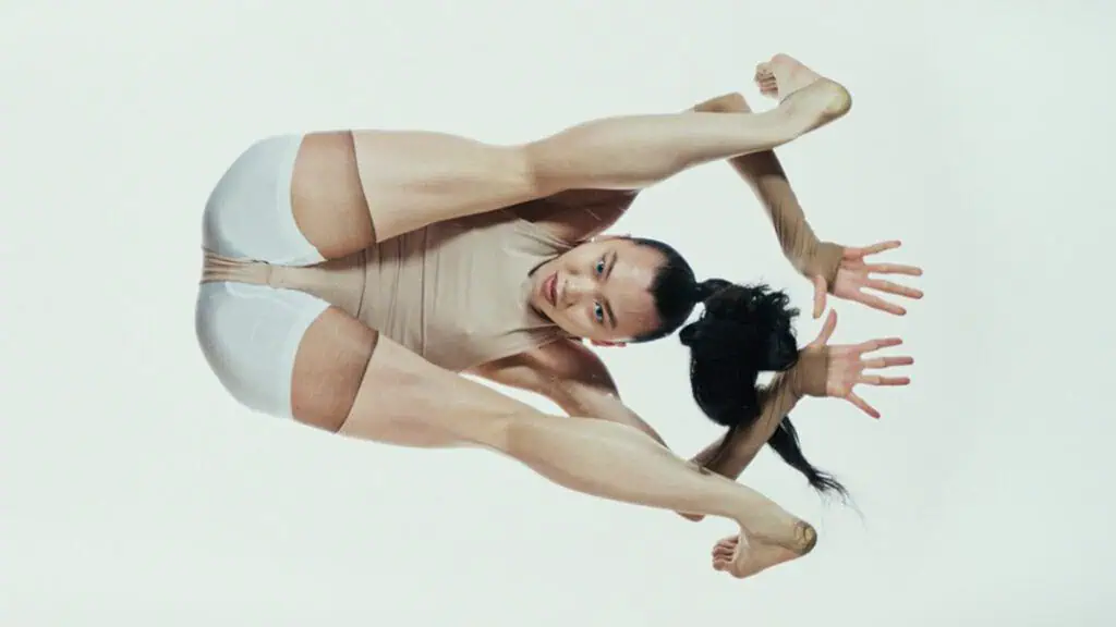 Contortionist performer striking an extreme pose in a minimalist studio for Bonnie Banane’s ‘Hoes of Na’.