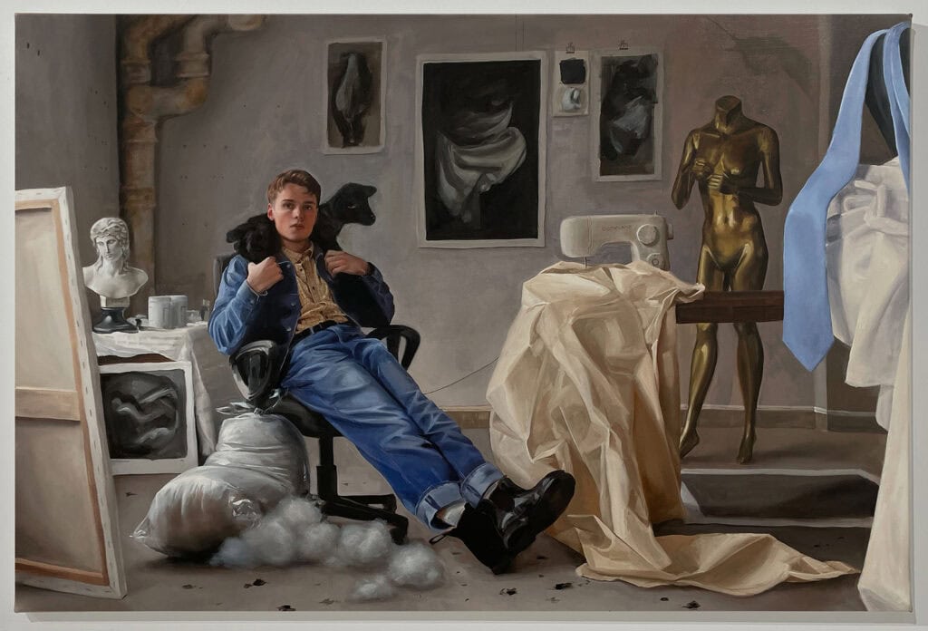 Full view of Conor Quinn’s painting Spring, depicting a young man reclined in a studio chair with a lamb over his shoulders, surrounded by draped fabrics, a mannequin, busts, and sketches in an atmospheric artist’s workspace.