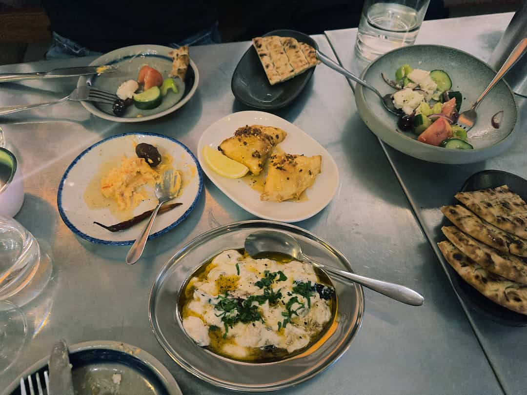 A selection of Greek small plates at Vori, including pita, tirokafteri, Greek salad, and filo pastries.